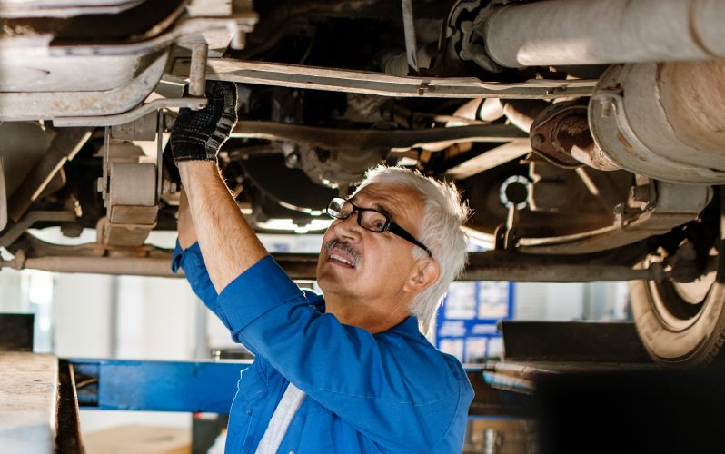 Mechanic standing beneath an automobile, working